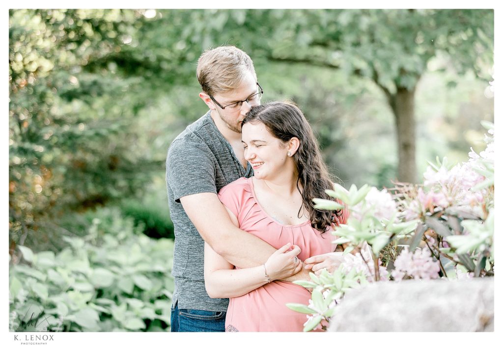 Man wearing grey t-shirt and a woman wearing a pink blouse hug each other during their Light and Airy Engagement session with K. Lenox photography