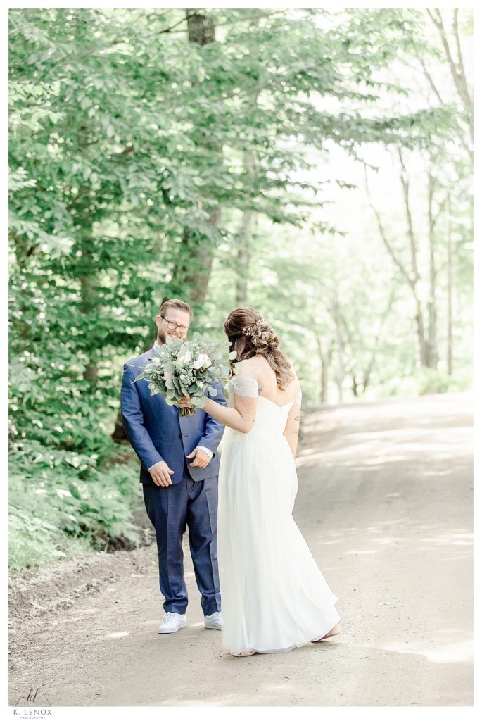 First look between a bride and groom on their wedding day at Mayfair Farm.  Couple is on dirt road, surrounded by trees. 