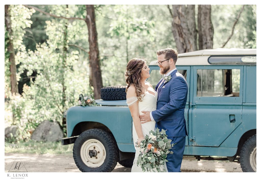 Bride and groom enjoy a moment together in front of a Blue Antique Land rover on their wedding day at Mayfair farm. 