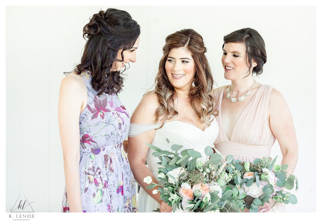A bride is candidly talking with her wedding party on her wedding day. 