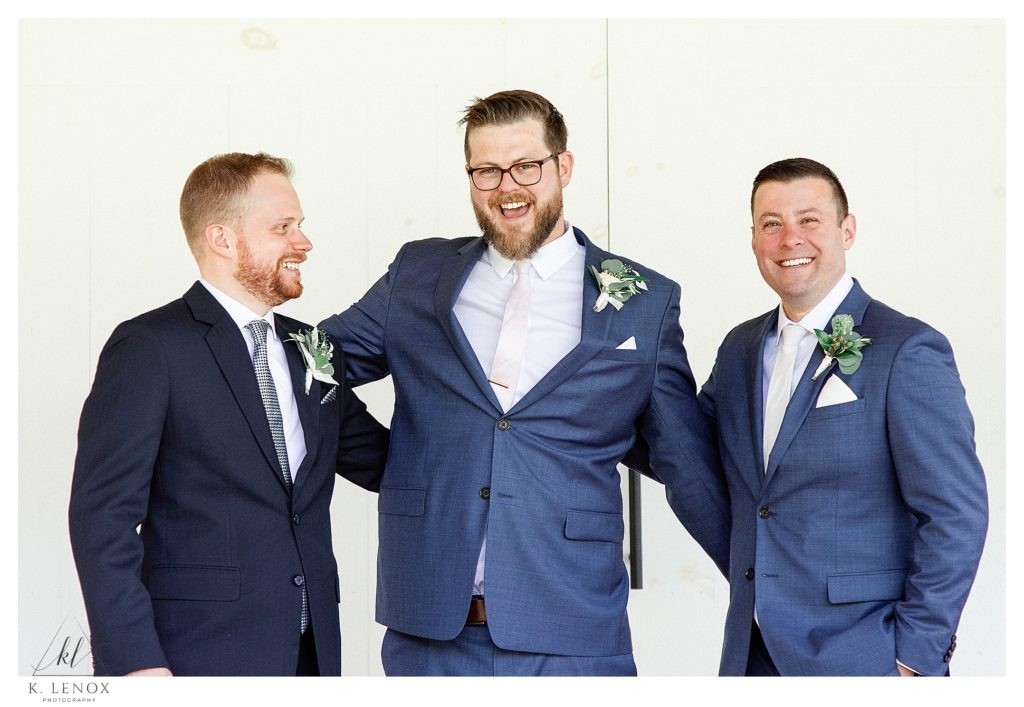 A groom and his two groomsmen laughing on the wedding day at Mayfair farm. 