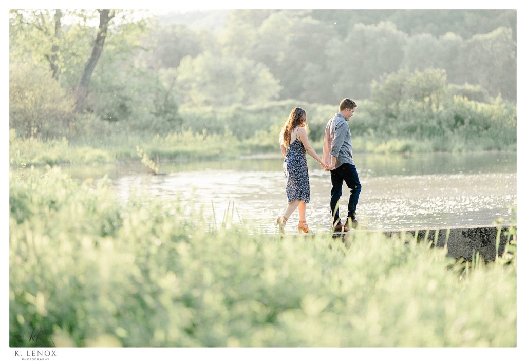Man and Woman walk along the CT river during their Outdoor Engagement Session in Brattleboro VT. 