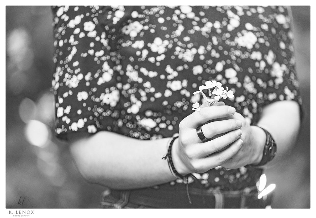 Black and White Photo showing a close up of person holding white flowers. 
