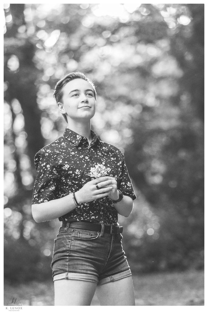 Black and White portrait showing a girl wearing a floral button down shirt and holding flowers.   Badass Senior Portrait session. 