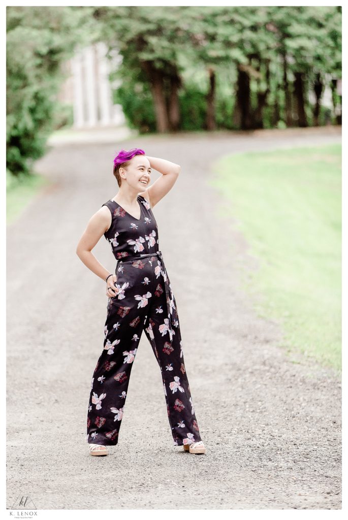 Candid portrait of a girl with Purple hair, and wearing a black floral jumpsuit.  