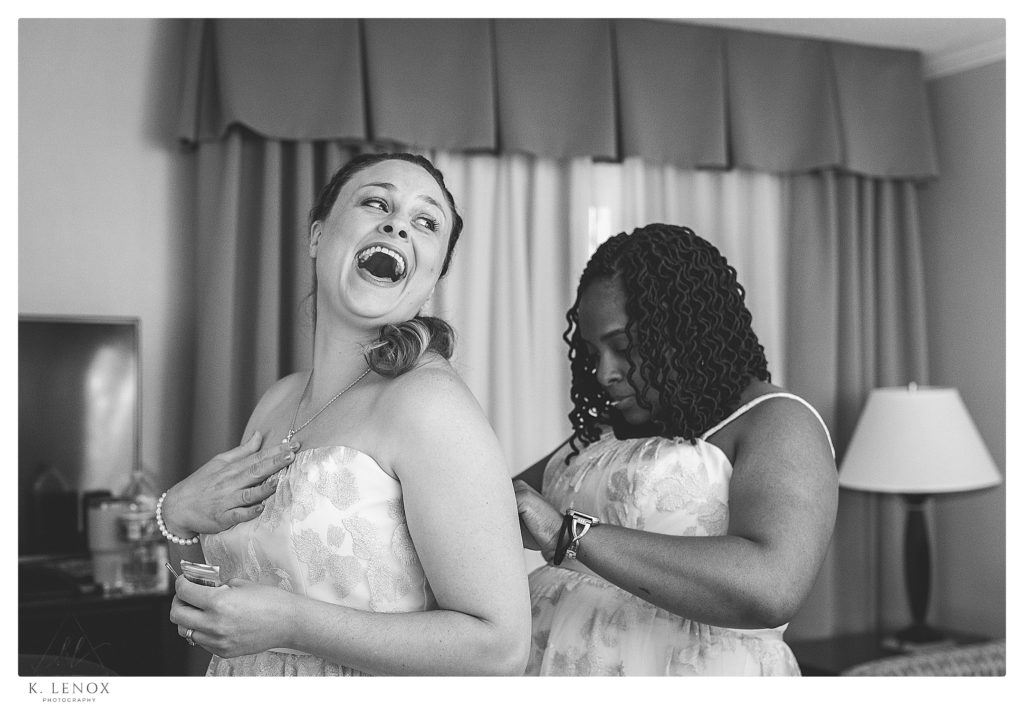 Black and white photo of  two women helping each other into their wedding bridemaids dresses. 