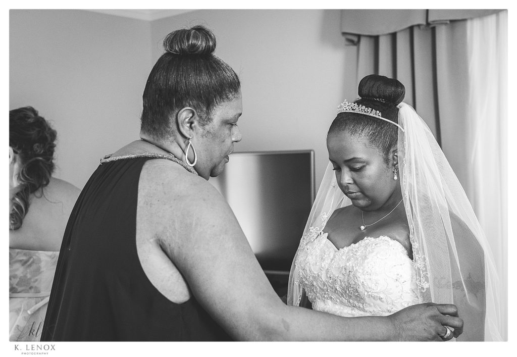 Black and White photo of a Mom helping her daughter bride into her dress and offering some prayer