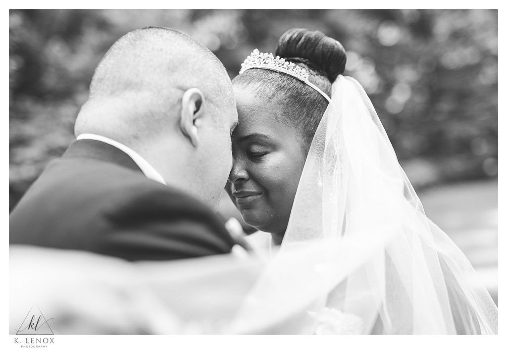 Black and White Photo of a Bride and Groom forehead to forehead.   A photo taken for their Classic Wedding at Alpine Grove