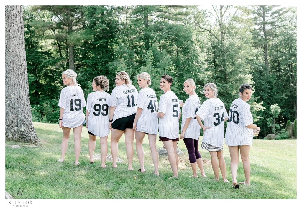 Brides and Bridesmaids all wear matching striped baseball jerseys while they toast with Champagne. 