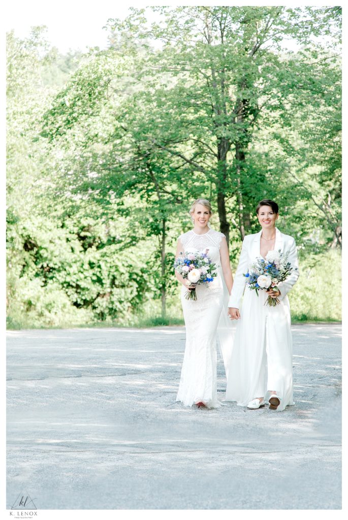 Two brides walking hand in hand on their summer wedding day at Mount Sunapee. 