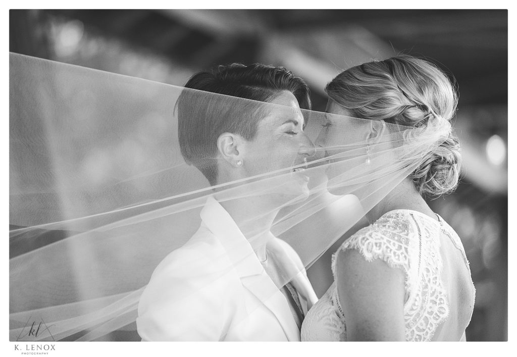 Black and White photo showing two brides about to kiss on their summer wedding at Mount Sunapee. 