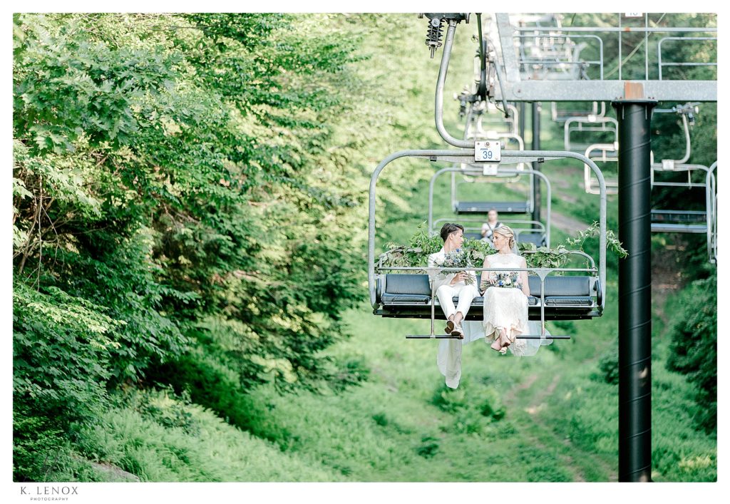 Two brides riding the ski lift down the mountain after their Summer wedding at Mount Sunapee. 