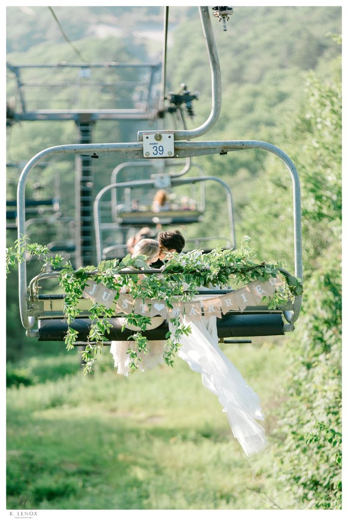 Two brides riding the ski lift down the mountain after their Summer wedding at Mount Sunapee. 