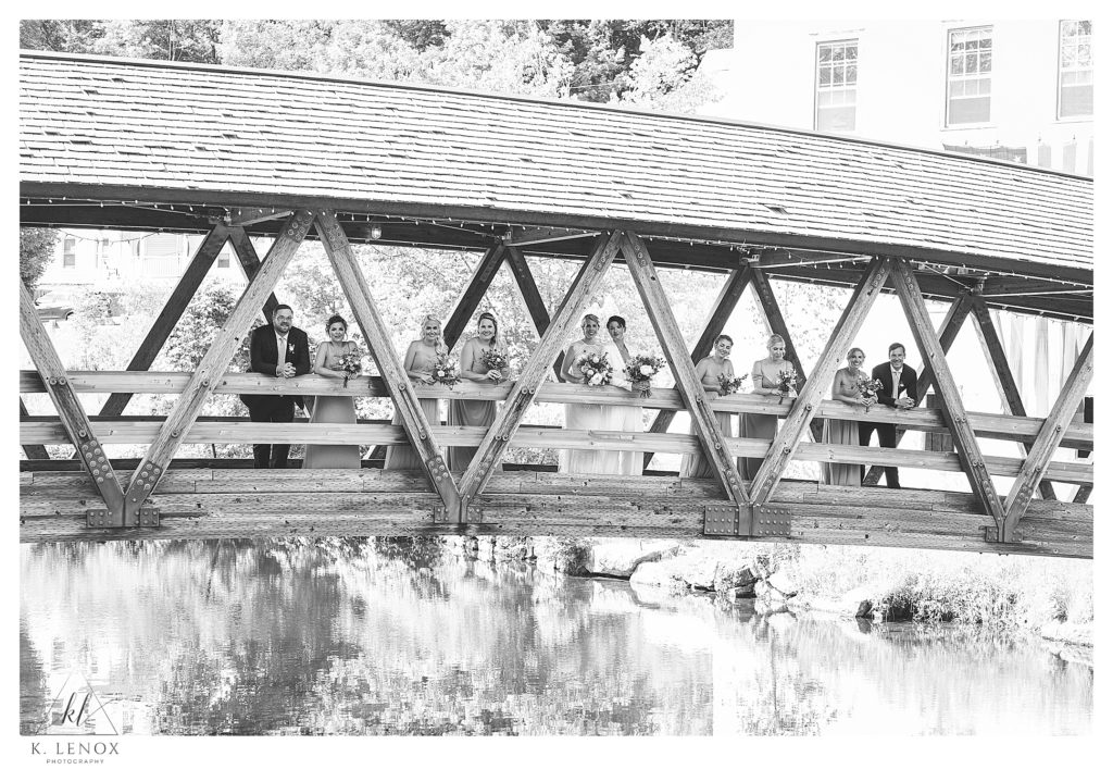 Black and White photo showing a wedding party on a Covered bridge near mount sunapee. 