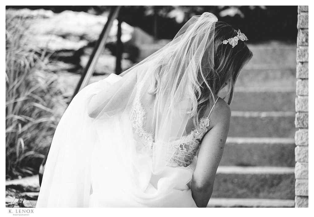 Candid black and white photo showing the back of a bride and the veil. 