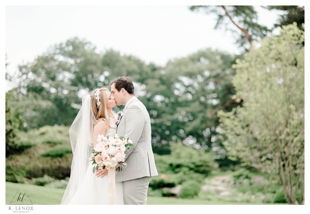 Light and Airy Photo showing a bride and groom kissing before their wedding at the York Golf and Tennis Club in Maine. 