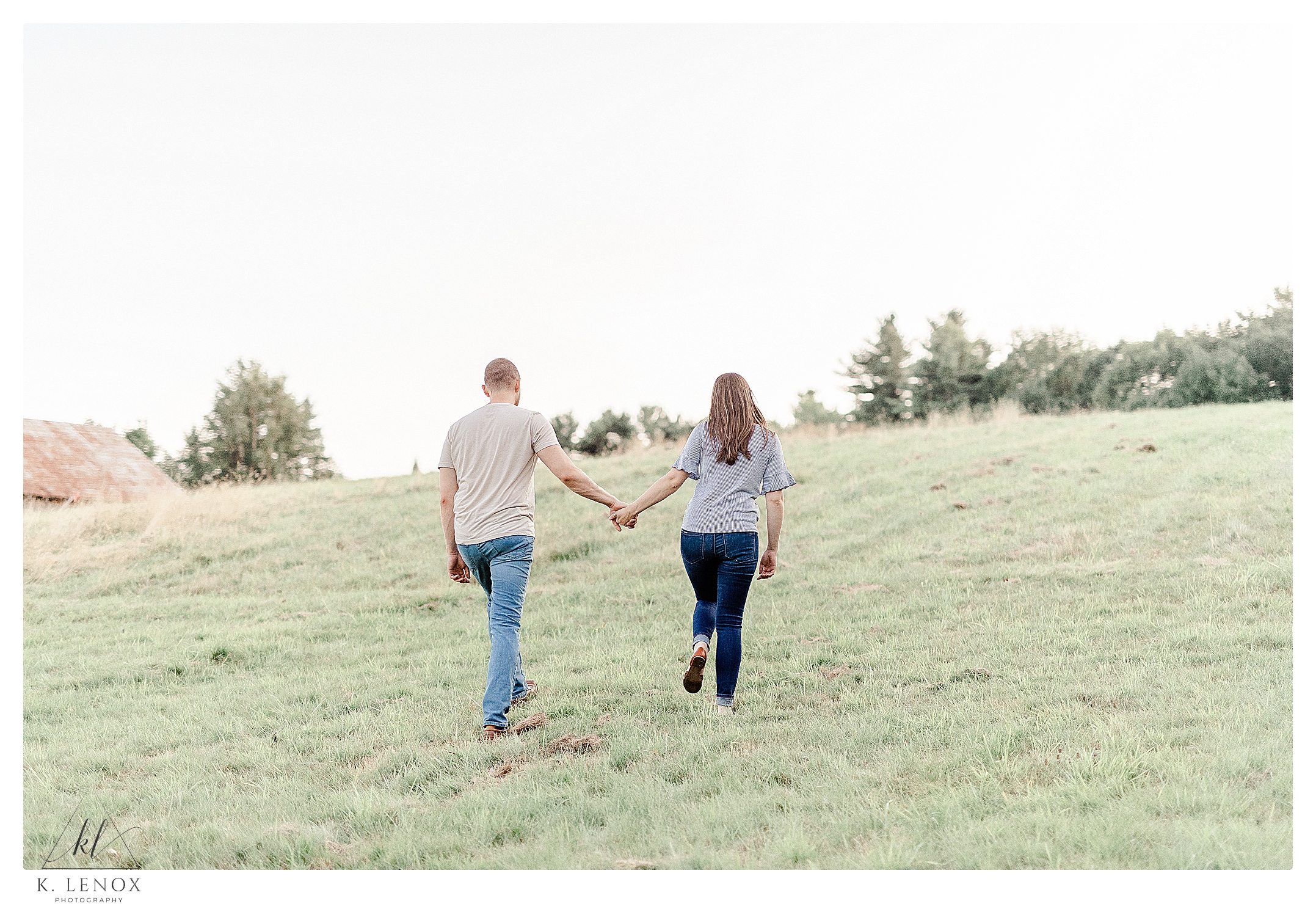 Man and Woman walking up a hill holding hands during their engagement session at Cathedral of the Pines