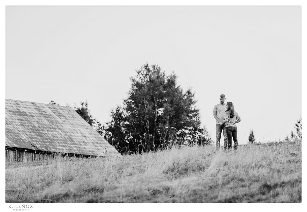 Black and White Photo of a Man and woman standing on a hill during their engagement session at Cathedral of the pines