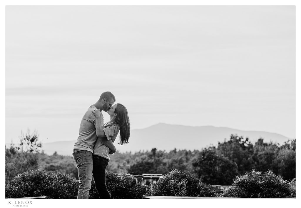Black and White Photo of a Man and woman kissing during their engagement session with Mount Monadnock in the background. 