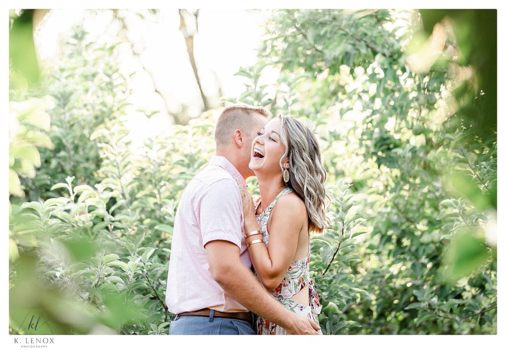 Light and Airy Engagement session at Alyson's Orchard showing a man and woman laughing in each others arms. 