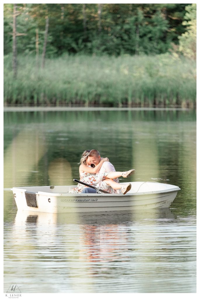 Candid photo of a man and woman sitting in a row boat at Alyson's orchard during their summer engagement session. 