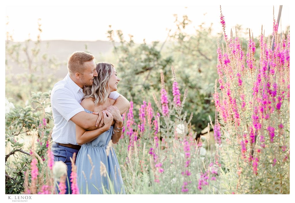 Light and Airy engagement session at Alyson's Orchard showing a pretty blonde woman and a handsome man standing in a field of purple flowers. 
