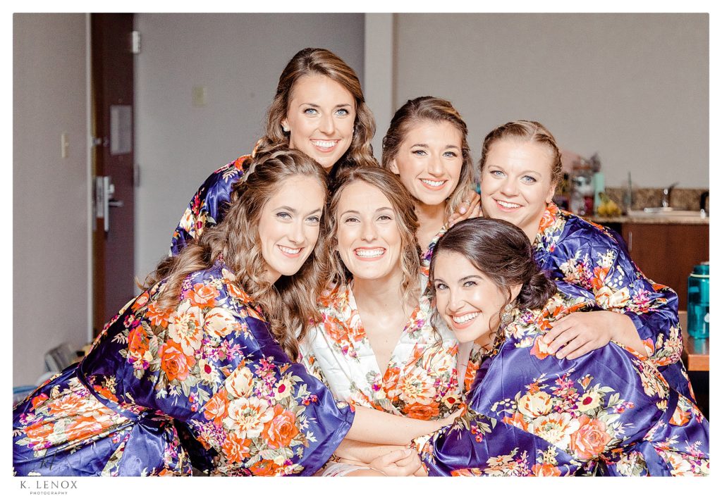 The Bride and her 5 attendants all wearing silk floral robes and posing for a photo before the Summer wedding at Birch Wood Vineyard. 