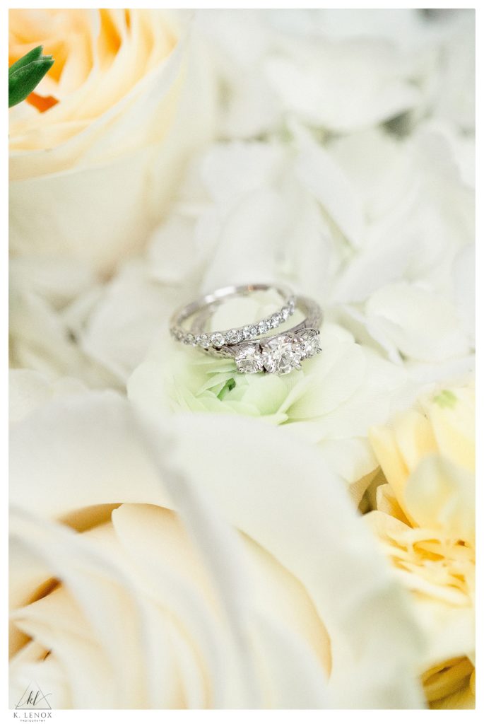 White Gold Diamond Present past and future engagement ring with diamond wedding band.  Photographed on a pale yellow and white bridal bouquet. 