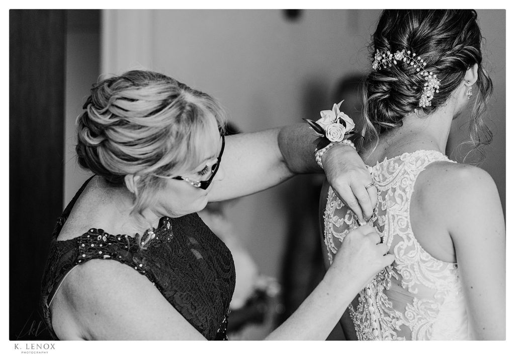 Black and White photo a mom helping button her daughters Essence of Australia fit and flare lace wedding dress with halter neckline, romantic completely lace back with fabric buttons. 