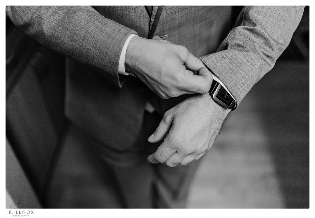 Black and white close up photo of a man adjusting his cufflinks and his watch, before his wedding day. 
