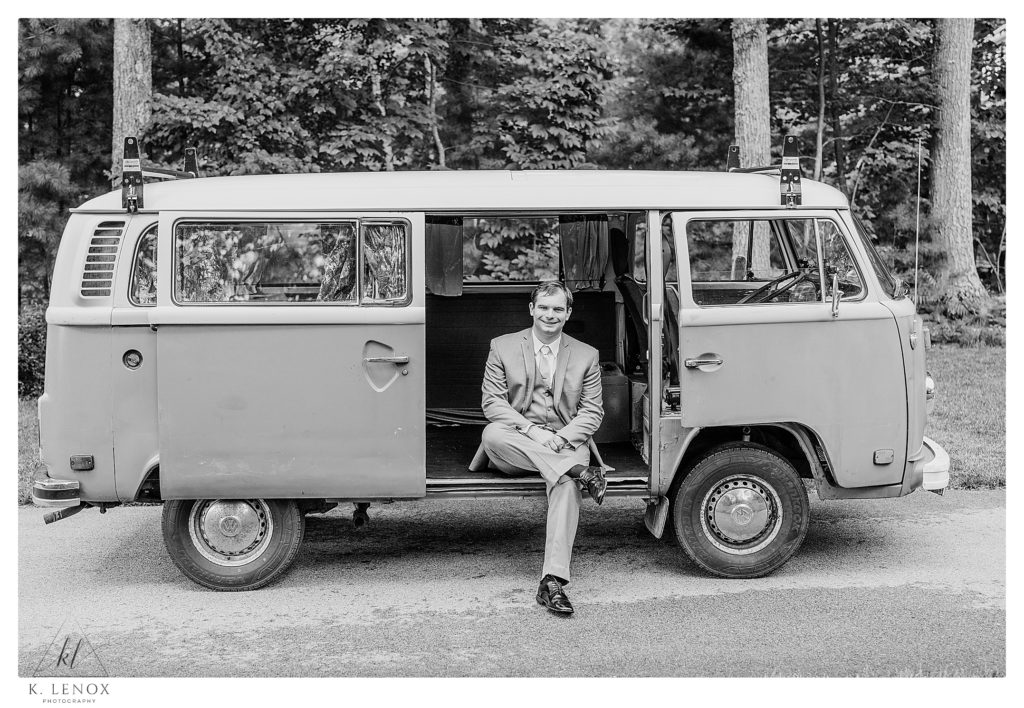 Black and White Photo of a Groom sitting in a 1978 VW Bus. 