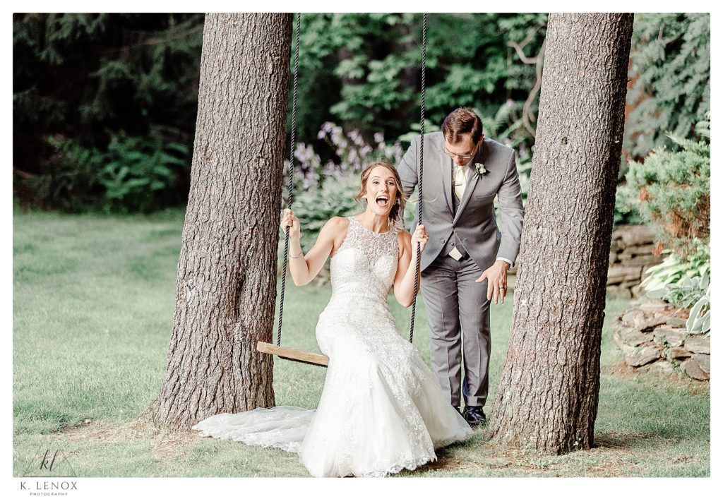 A candid photo of a bride and Groom swinging on the tree swing during their Summer Wedding at Birch Wood Vineyard 