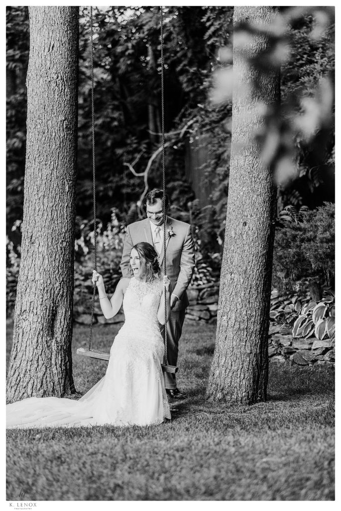 Candid Black and White photo of a Bride and Groom during their Summer Wedding at Birch Wood Vineyard.  on the Tree Swing. 