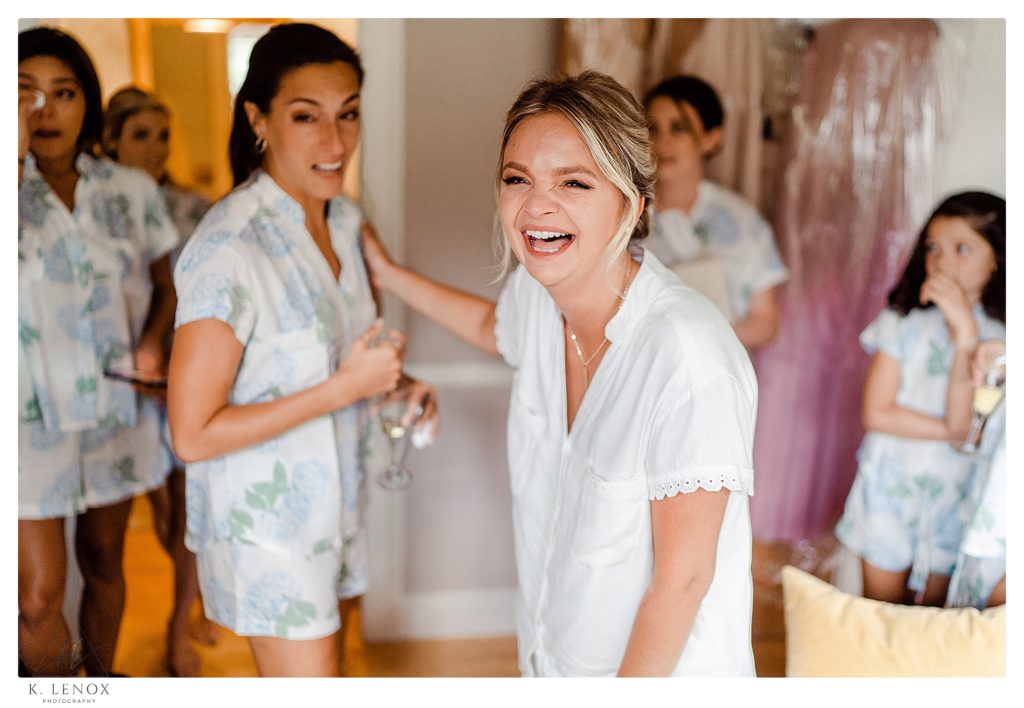 Candid photo of a bride to be wearing a white shirt and laughing with a tear in her eye. 