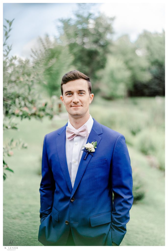 Light and Airy Formal portrait of a Groom wearing a blue suite and a white flower boutonniere 