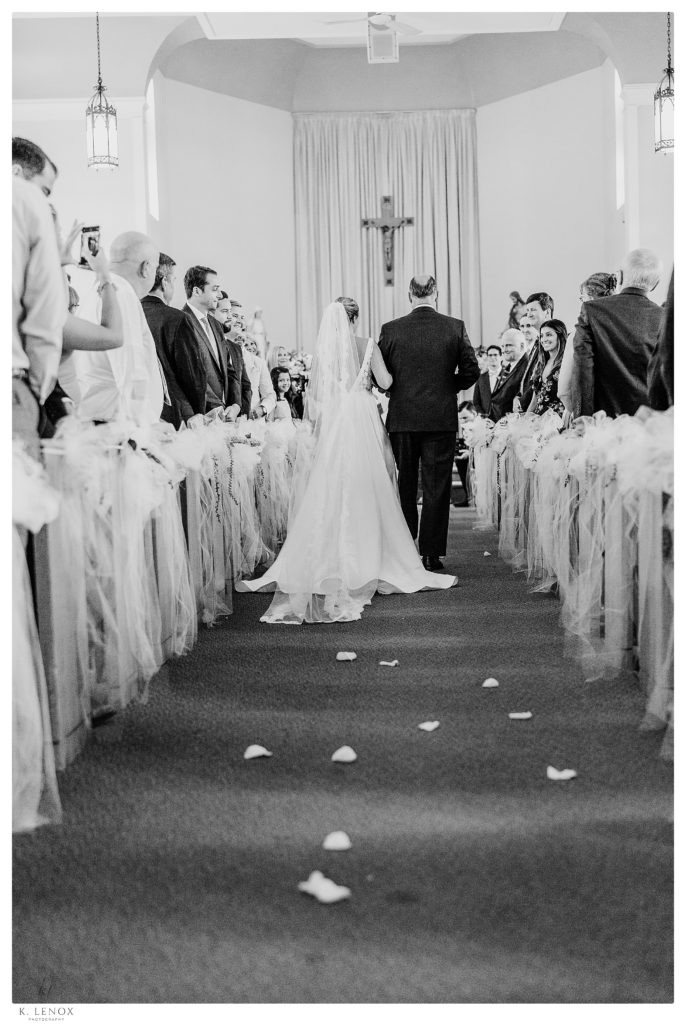 Black and White photo of a Bride and her dad walking down the aisle at ST. Andrew's Church in Waterbury VT. 