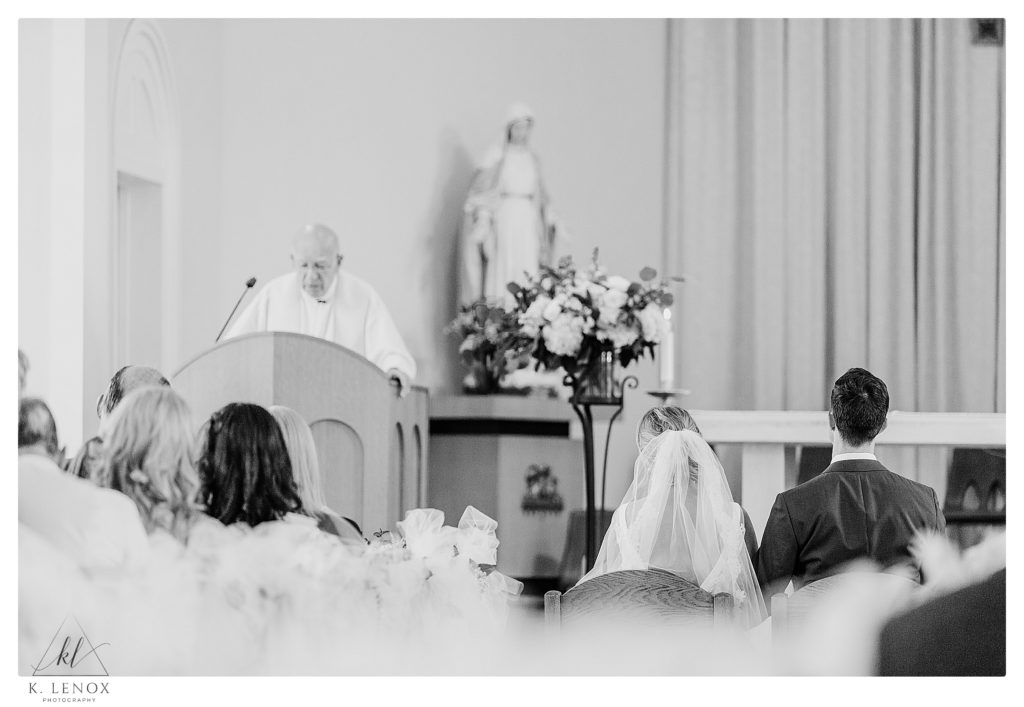 Black and White Photo showign the bride and Groom sitting in Church at St. Andrews in Waterbury VT