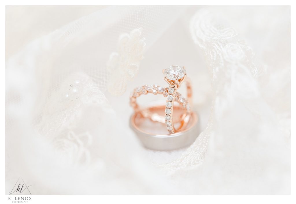 Rose gold and diamond wedding ring set photographed surrounded by a laced veil. 
