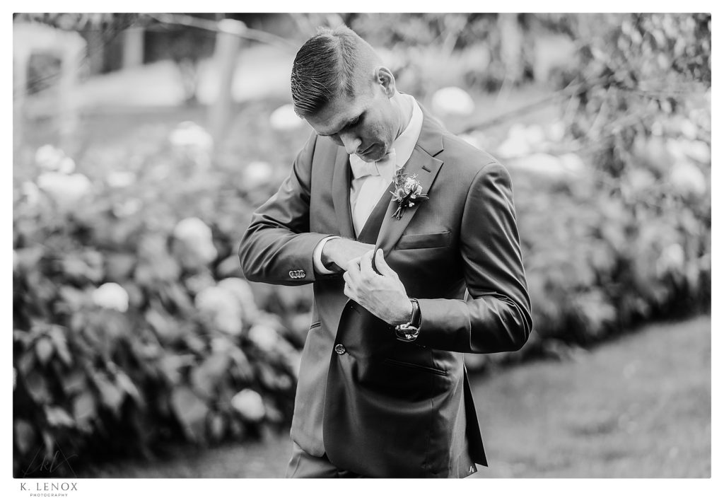Black and White photo of a groom fixking his pocket before his Wedding at The West Mountain Inn