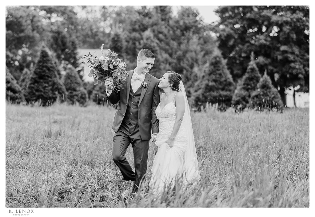 Candid, Black and White Bride and Groom walk hand in hand through a field in Arlington Vermont. 