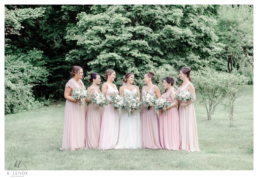 Wedding party wearing pastel pink dresses pose for a portrait at the West Mountain Inn. 
