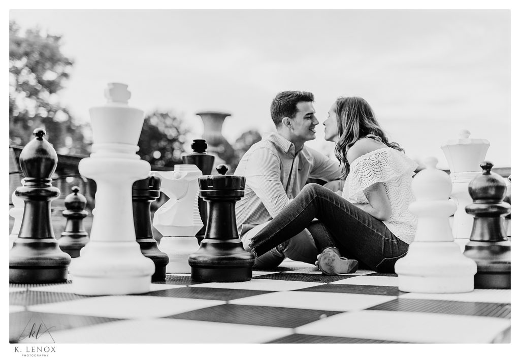 Black and White photo showing a man and woman sitting on a life sized chess board while at the Crane Estates. 
