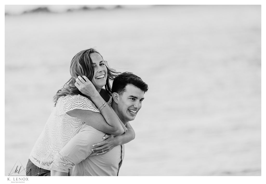 Black and White photo of a man and woman giving a piggy back ride on the beach at Crane Estates. 