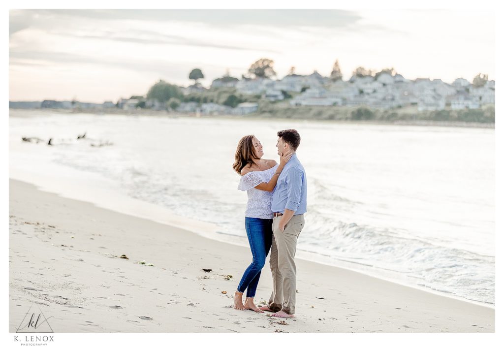 Light and Airy photo taken on the beach during an Engagement Session at the Crane Estates.  Photo shows a man and woman standing close together. 