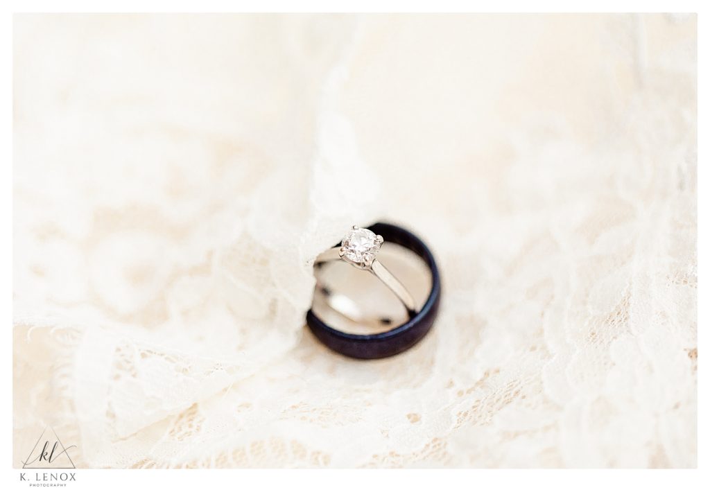 White gold and Diamond engagement ring with a black mens wedding band, photographed on an ivory wedding dress with lace. 