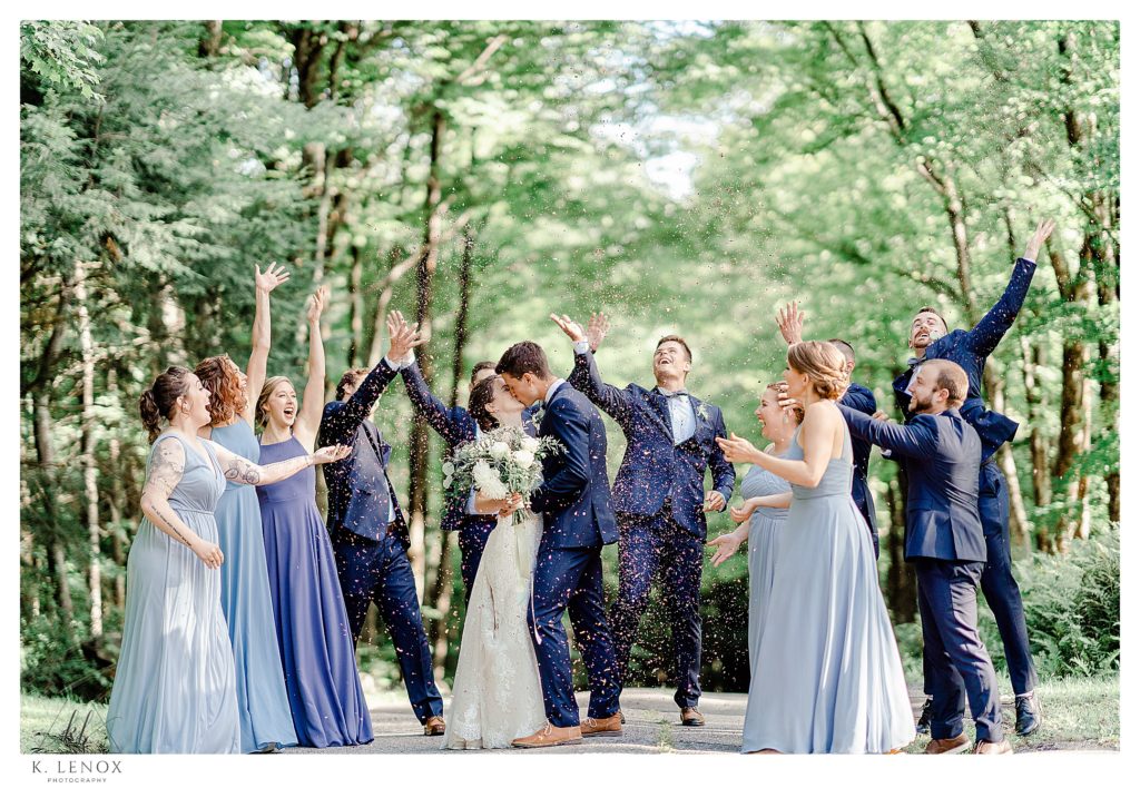 Wedding party throws flower petals on the bride and groom for a light and airy photo. 