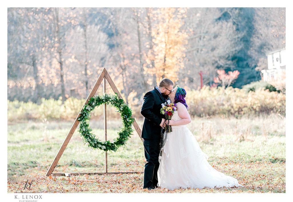 Bride and Groom kiss in front of the Deathly Hallows for their Harry Potter Themed wedding at Stonewall Farm in Keene NH. 