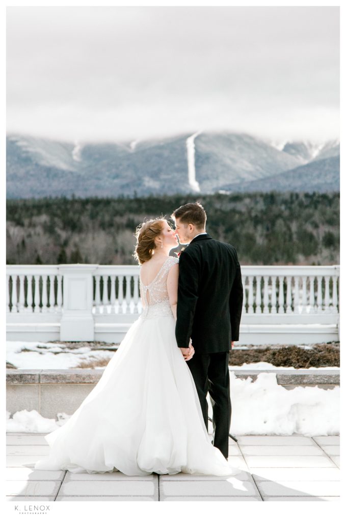 Winter Wedding at the Omni Mount Washington Resort.  Picture shows a bride and groom kissing with a view of the mountains behind them.  