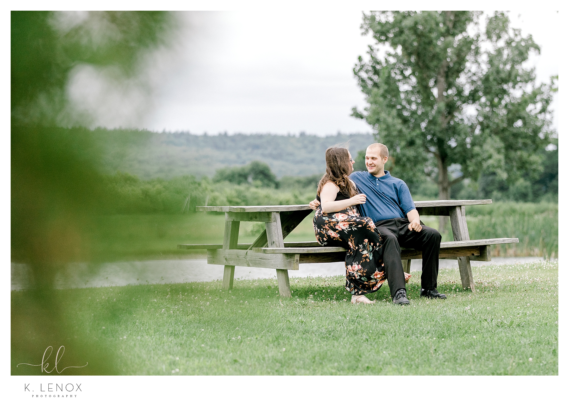Man and woman sit at a picnic table while at Alyson's Orchard for their Bright and Airy Engagement Photos. 