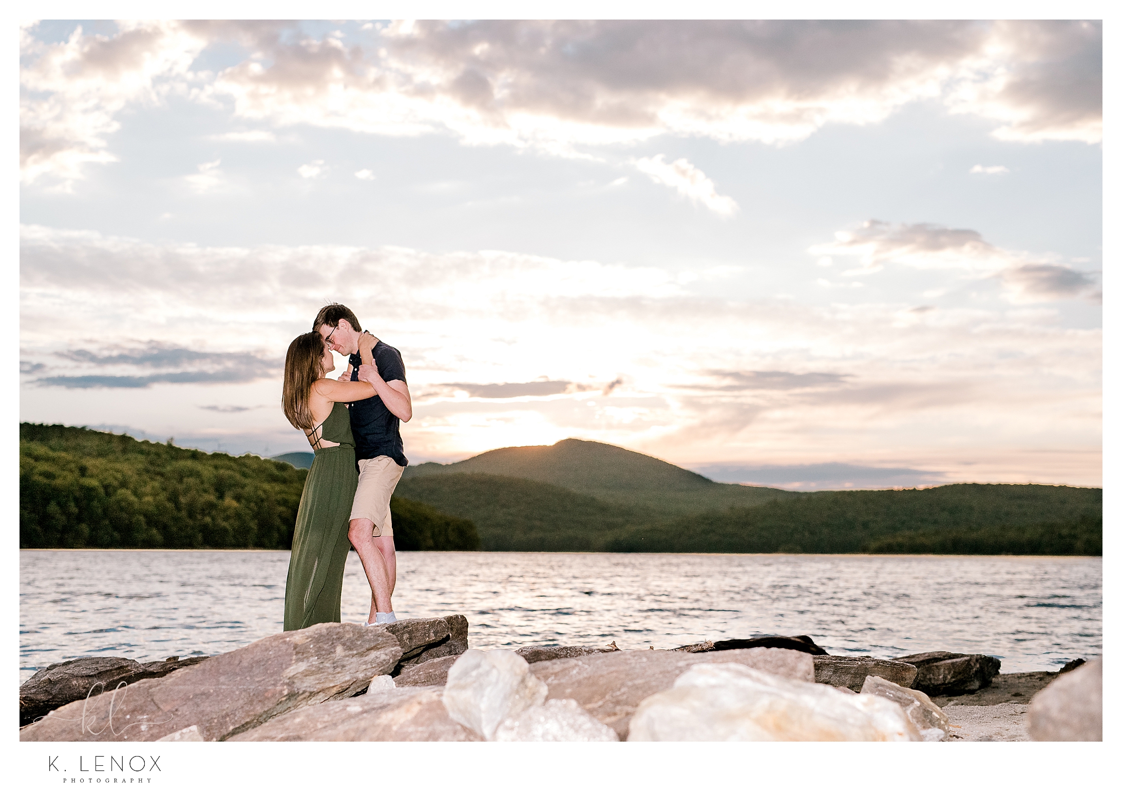 Engagement Session on the shore of the Harriman Reservoir in Wilmington VT.   Man and Woman together on the rocks at sunset. 